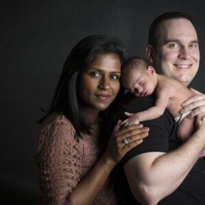 Family portrait in studio with ten day old newborn baby on Dad's shoulder love