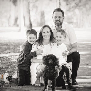 family of four dressed up and with a black poodle