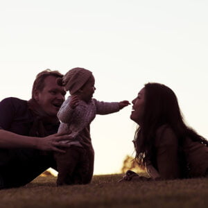 couple with young baby laying down at sunset